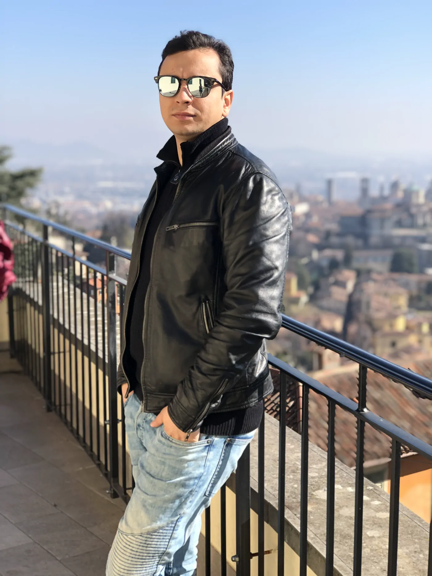 Abozar Alizadeh in a black leather jacket and mirrored sunglasses, on a terrace above Bergamo
