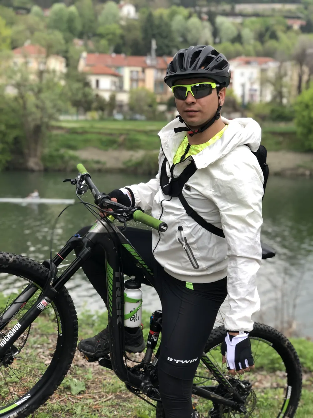Abozar in a white jacket and helmet on his mountain bike by the river Po