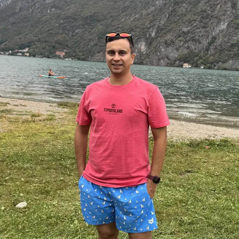 Abozar in a red t-shirt on the grassy shore of Lake Lugano