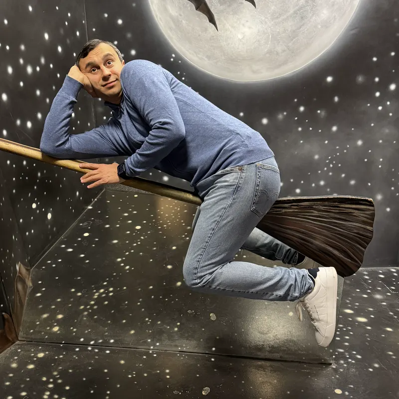 Abozar posing on a painted broom flying under a big moon with bats