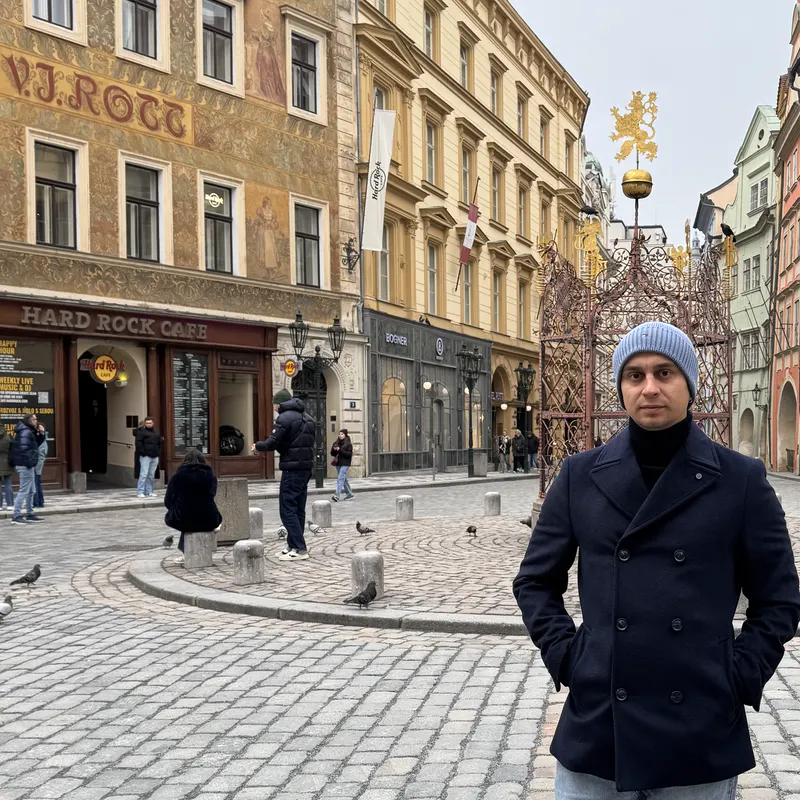 Abozar in a navy coat and beanie on a cobbled square in Prague's Old Town