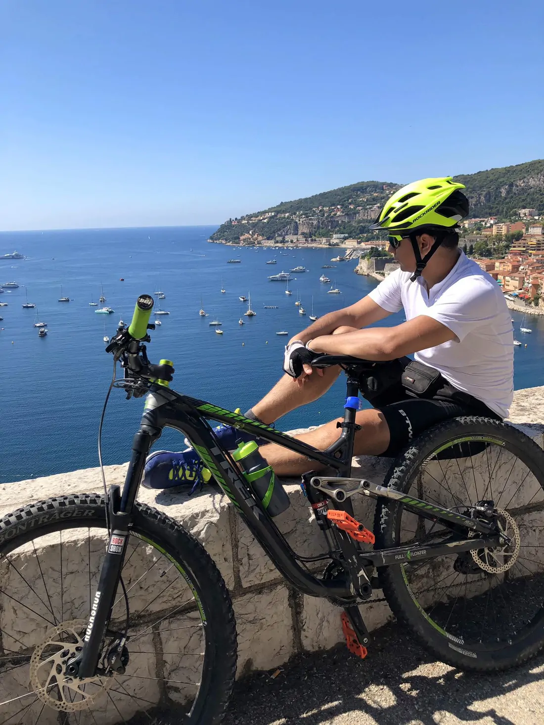 Abozar resting next to his mountain bike, looking out over a bay full of boats on the Côte d'Azur