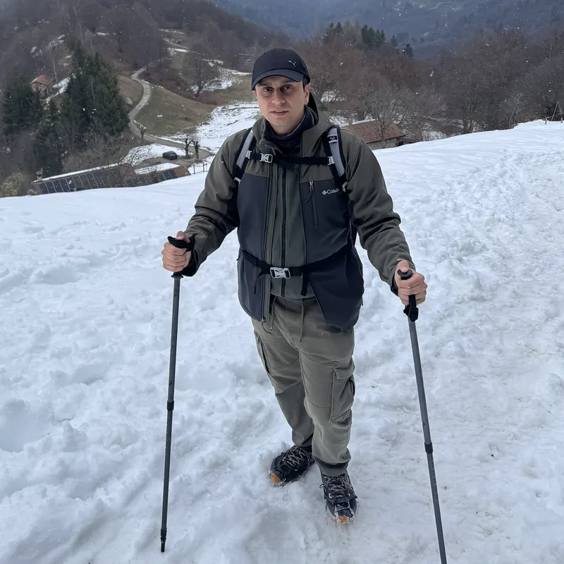 Abozar with trekking poles on a snowy slope above Lake Como