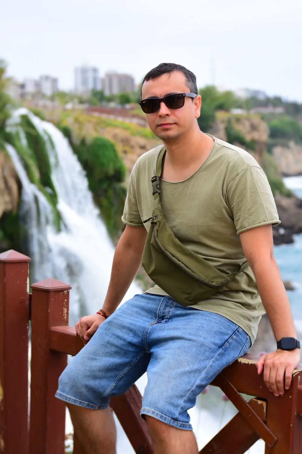 Abozar sitting on a red wooden railing next to a big waterfall